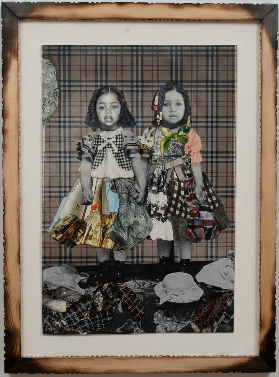 a collage of black and white photos and colorful textiles in a carved wooden frame. the photo depicts two little girls