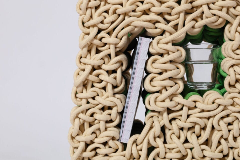 a detail of a small side table with niches for objects, made from beige nylon rope
