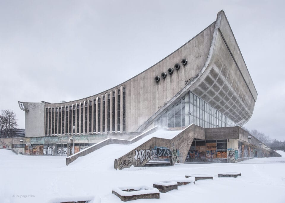 a brutalist, concrete, Soviet-era building with a large, swooping roofline, pictured in winter