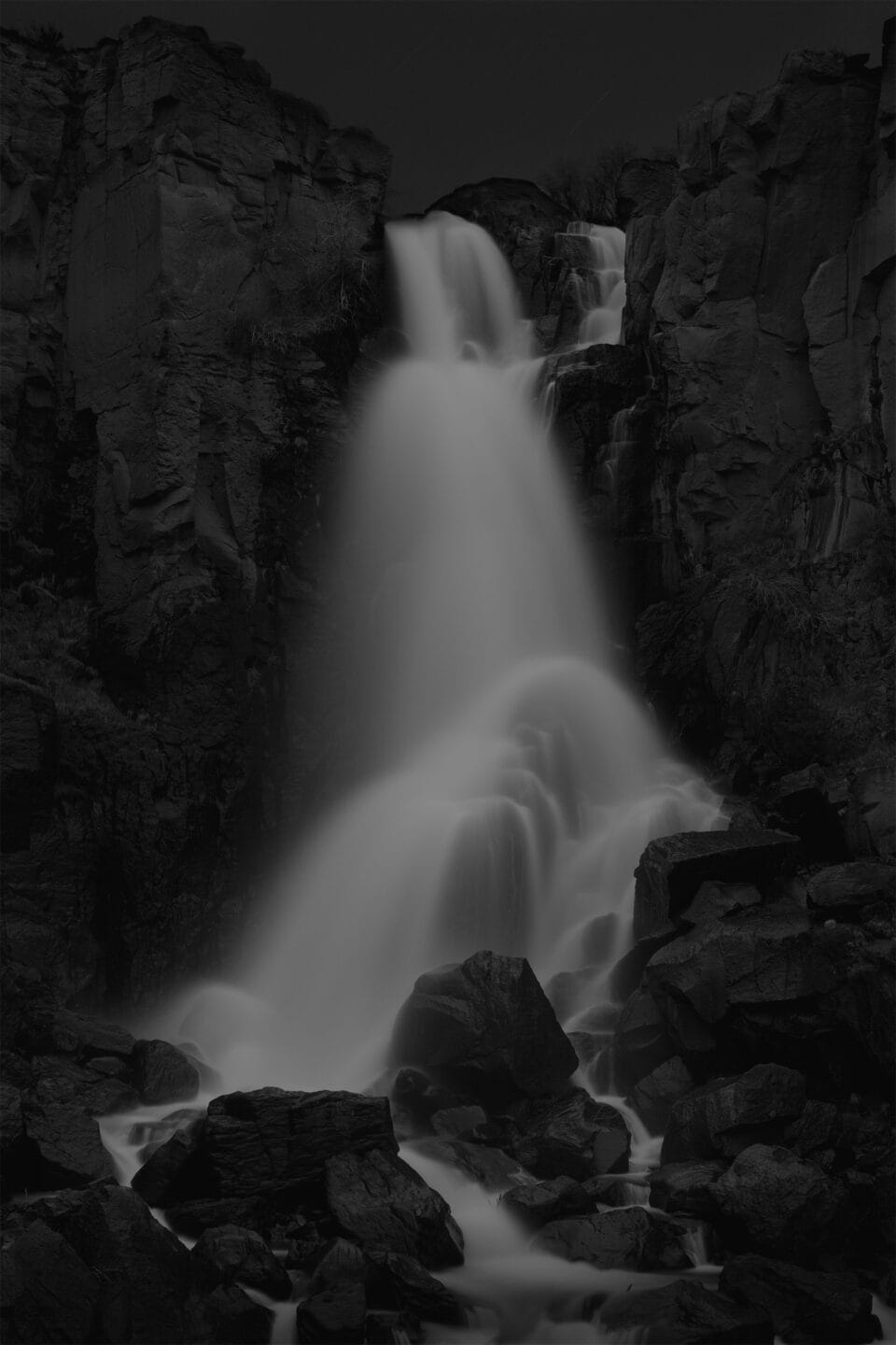 a moody black and white image of a waterfall