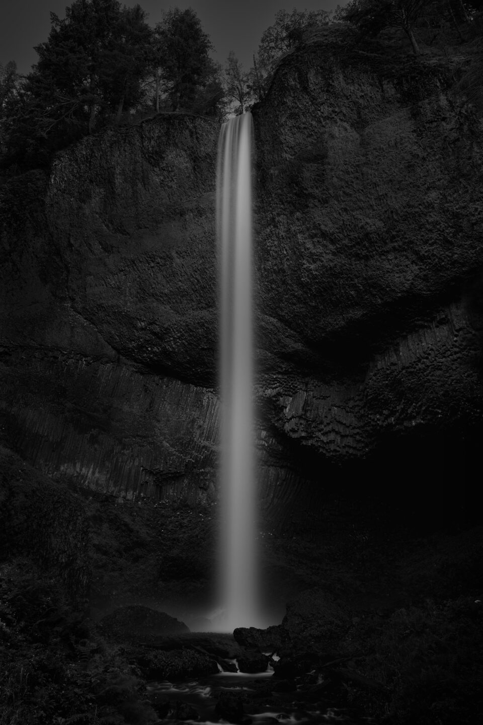 a moody black and white image of a waterfall