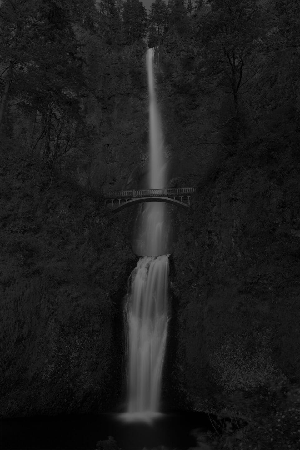 a moody black and white image of a waterfall