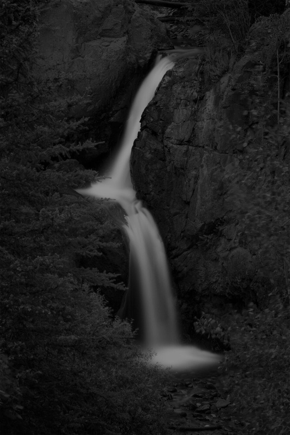 a moody black and white image of a waterfall