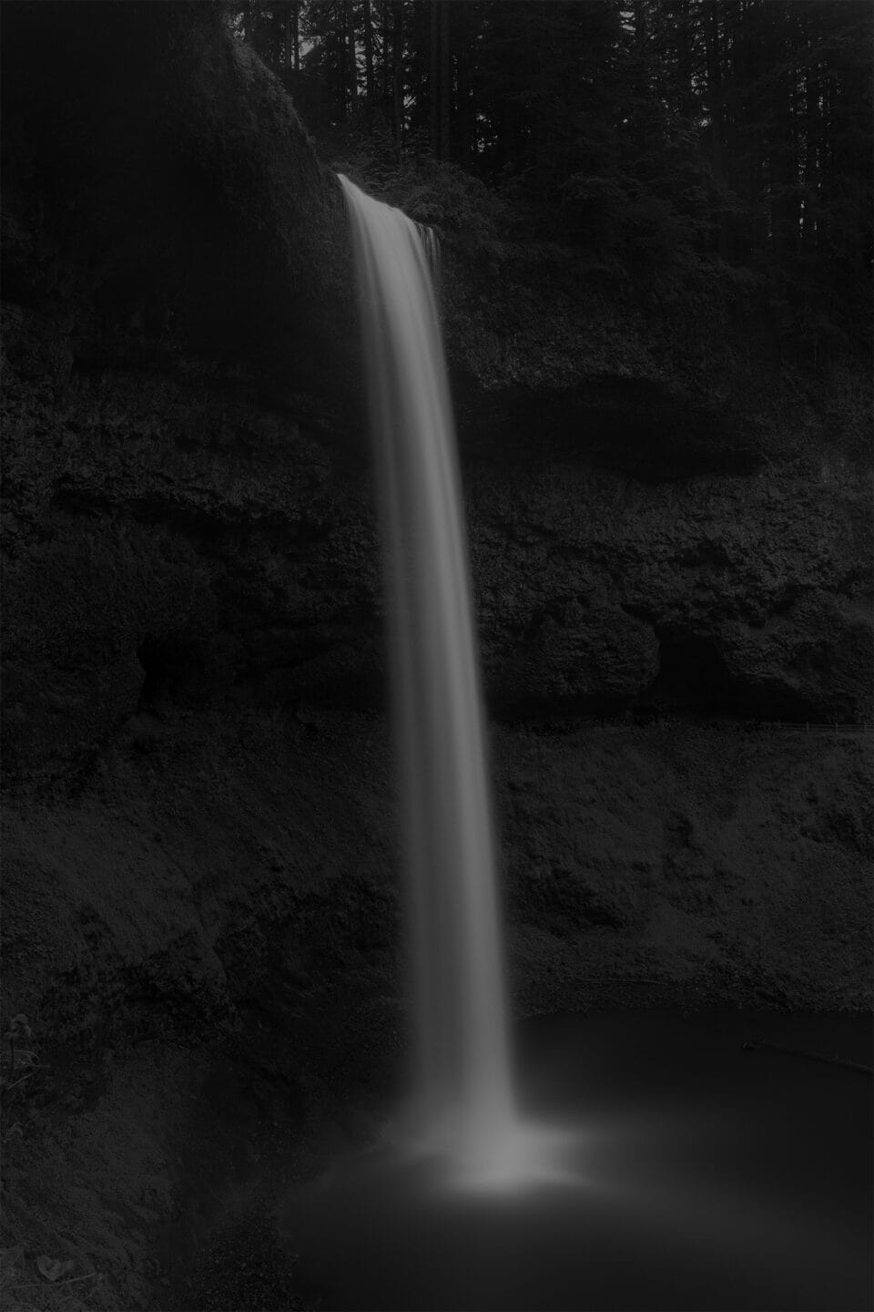 a moody black and white image of a waterfall