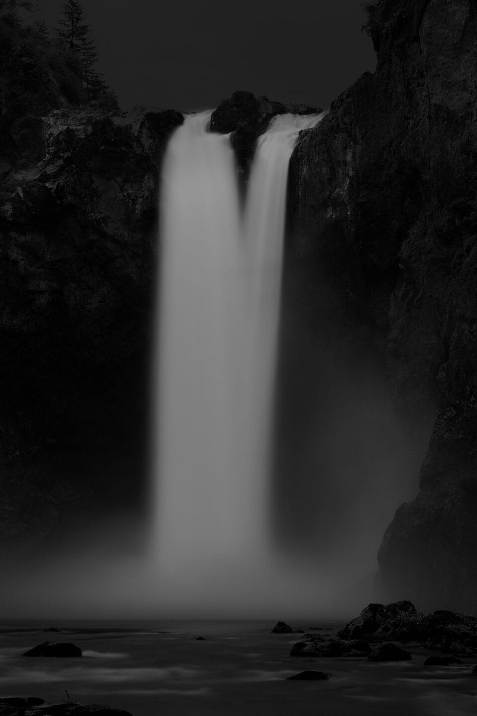a moody black and white image of a waterfall