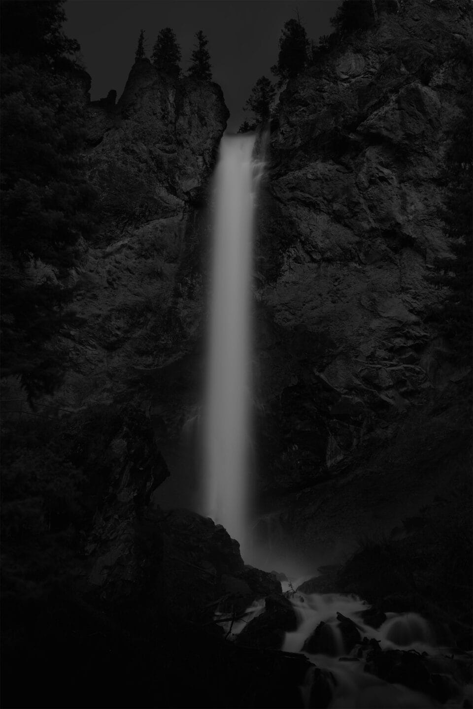 a moody black and white image of a waterfall