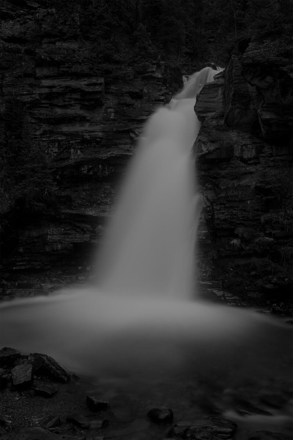 a moody black and white image of a waterfall