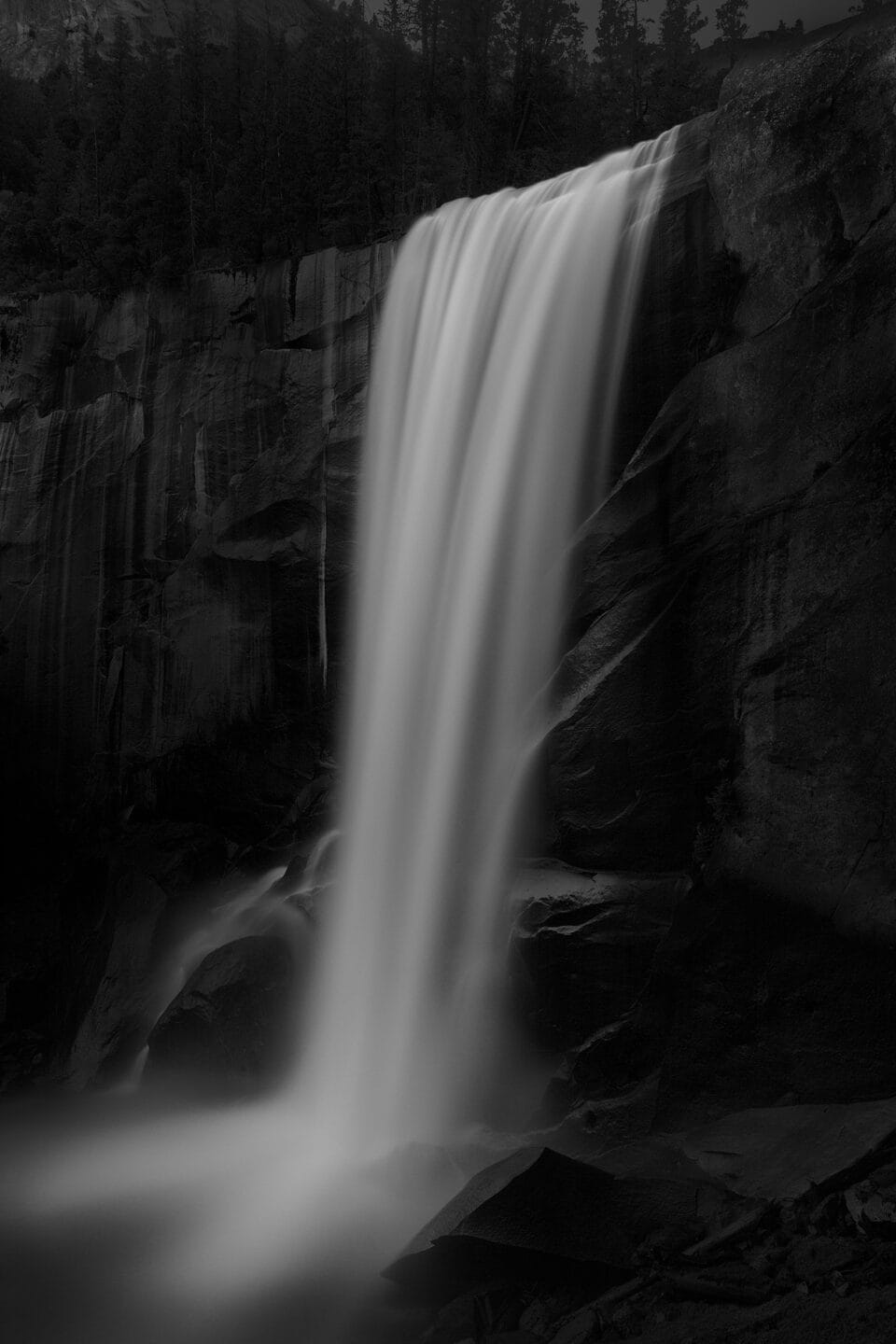 a moody black and white image of a waterfall