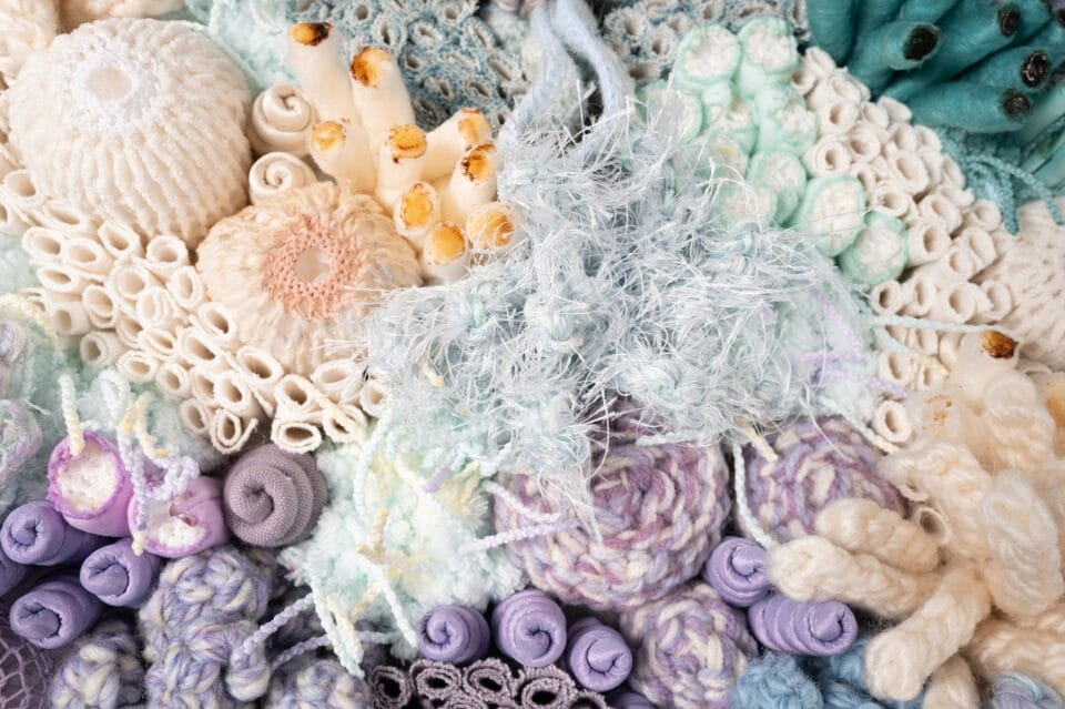 a detail of a vibrant fiber work evoking corals, molds, and other organic forms