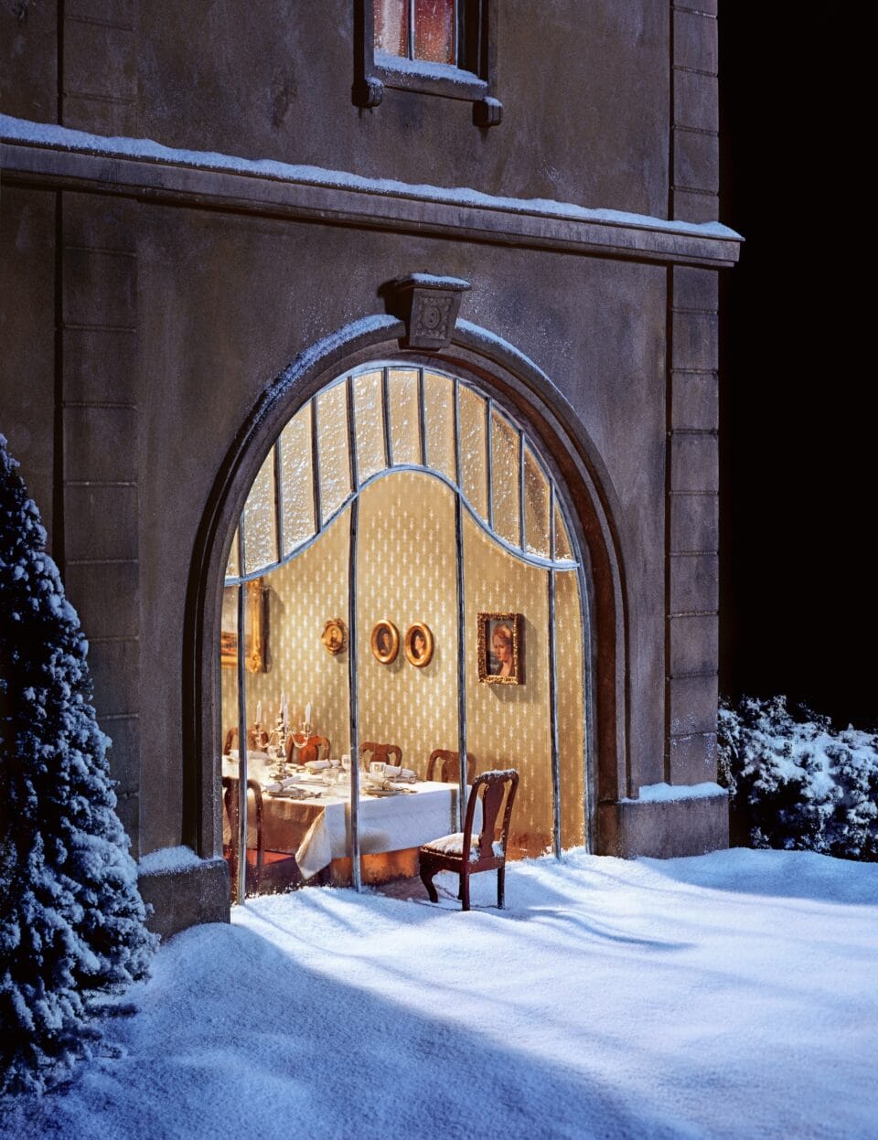 a photo of a miniature set showing an absurd scenario of a glass-fronted restaurant with snow outside, and a single chair and table are stuck outside, connected to the glass