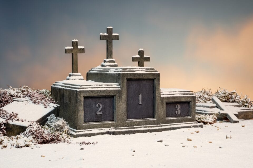 a photo of a miniature set or sculpture of an awards podium numbered 1, 2, and 3, with three crosses on top of each, as if merging an awards ceremony and a cemetery